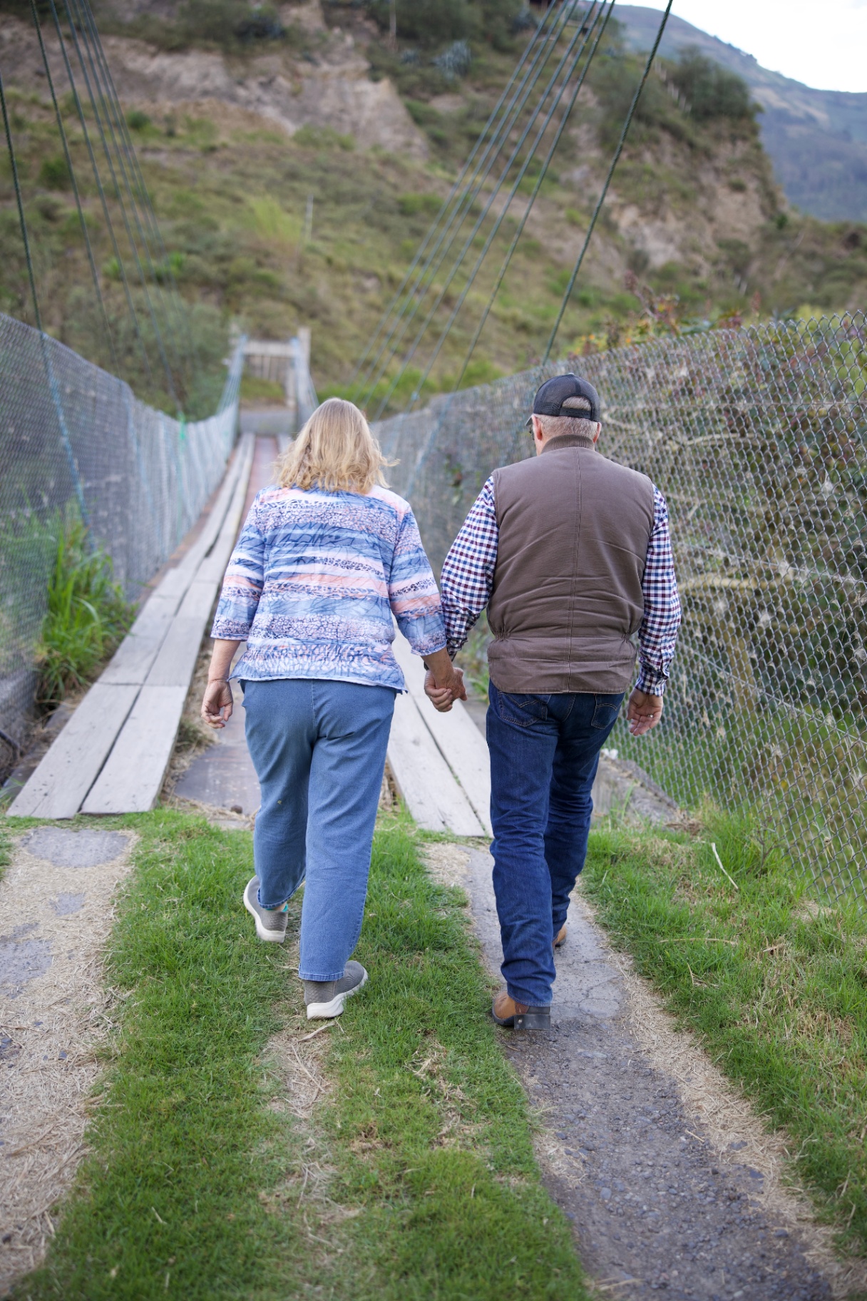 Steve and Carol Thompson walking hand in hand toward a footbridge in the Ecuadorian highlands